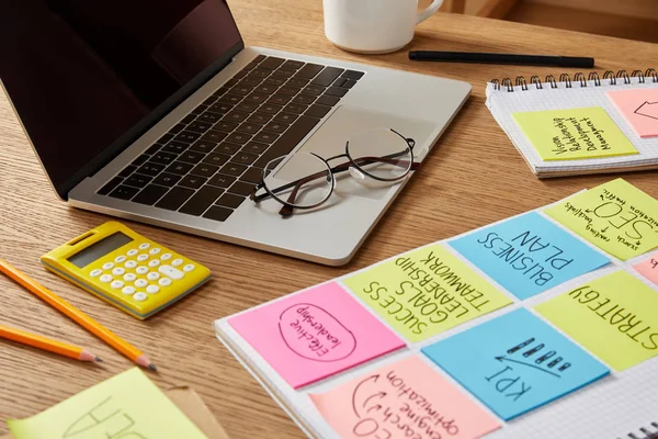 Adesivi carta con strategia aziendale, calcolatrice e laptop su tavolo — Foto stock