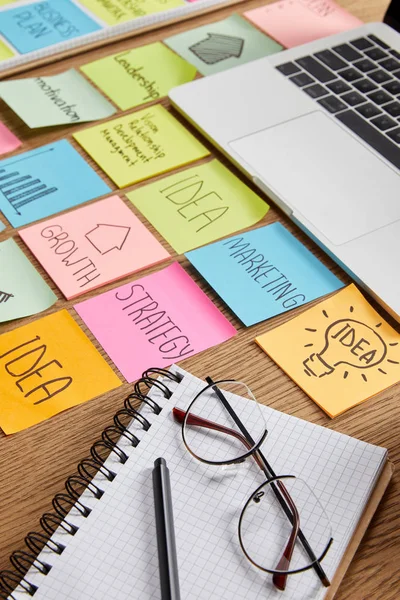 Paper stickers with business strategy, laptop and notebook with pencil on tabletop — Stock Photo