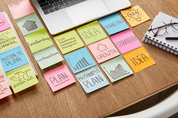 High angle view of paper stickers with business strategy and laptop on tabletop — Stock Photo