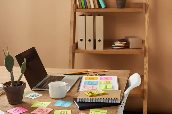 Adesivos de papel com estratégia de negócios, cacto e laptop na mesa — Fotografia de Stock