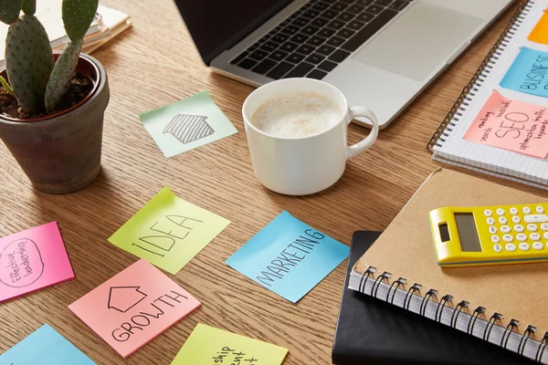 Hojas de papel de la nota con la estrategia de negocio, calculadora y computadora portátil en la mesa - foto de stock