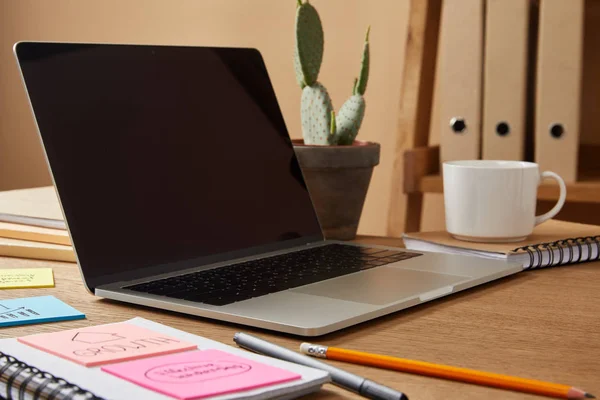 Laptop with blank screen and paper stickers on tabletop — Stock Photo