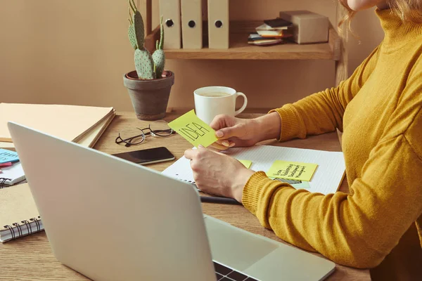 Cropped image of woman holding sticker with idea word at table at home — Stock Photo
