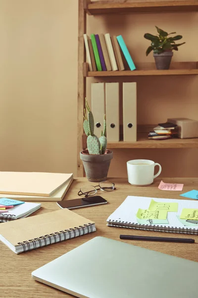 Adesivos de papel com estratégia de negócios e laptop com smartphone na mesa em casa — Fotografia de Stock