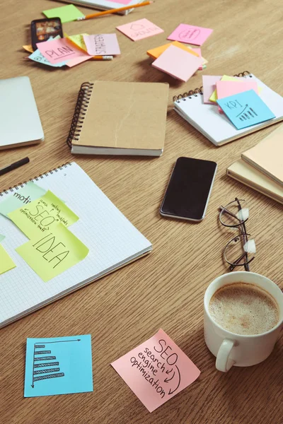 Adesivos de papel com estratégia de negócios e smartphone com tela em branco na mesa em casa — Fotografia de Stock