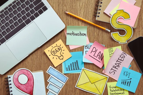 Top view of paper stickers with business strategy and laptop on table at home — Stock Photo