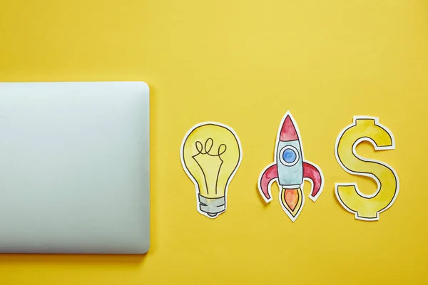 Top view of laptop and paper signs on yellow surface — Stock Photo