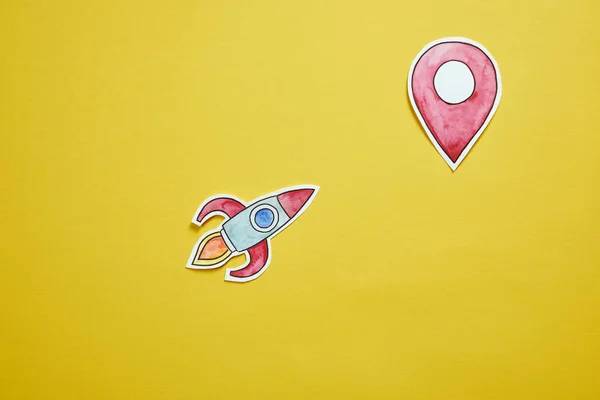 Top view of paper rocket and location sign isolated on yellow — Stock Photo