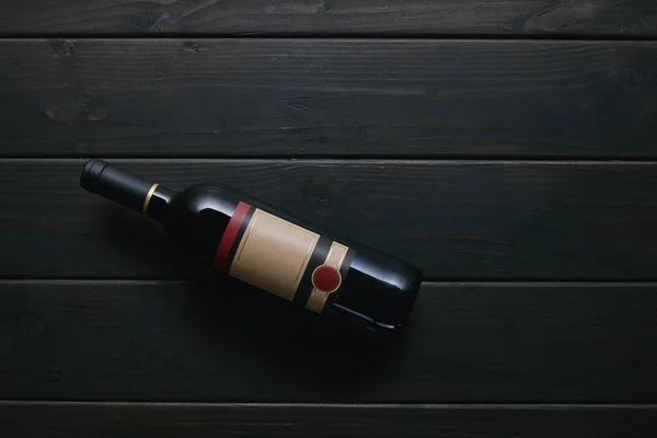 Vista superior de una sola botella de vino con etiqueta en blanco en la superficie de madera - foto de stock