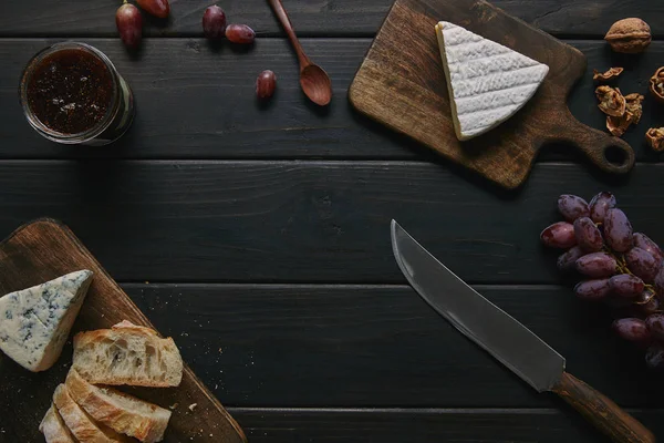 Vista superior del cuchillo, mermelada deliciosa y bocadillos gourmet en la mesa de madera - foto de stock