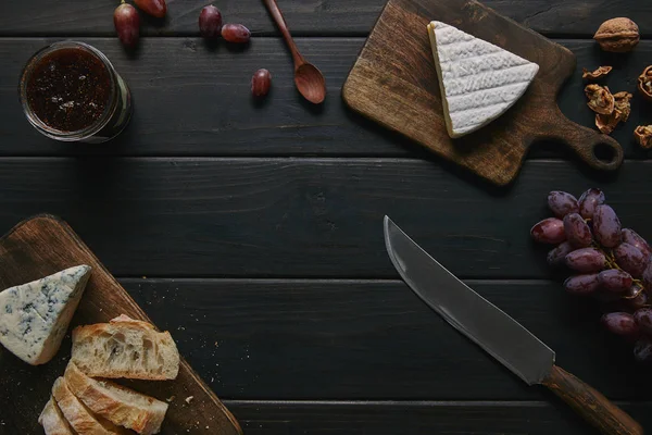 Top view of knife, delicious jam and gourmet snacks on wooden table — Stock Photo