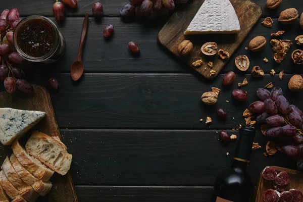Draufsicht auf Weinflasche und verschiedene leckere Snacks auf Holztisch — Stockfoto