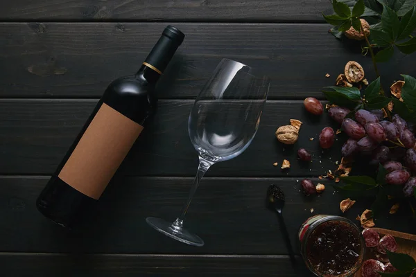 Top view of wine glass with bottle and grapes with nuts on wooden surface — Stock Photo