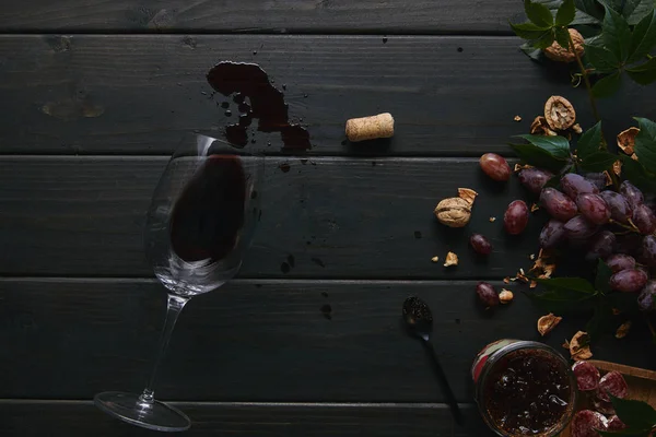 Top view of glass with red wine, cork and grapes with nuts on wooden surface — Stock Photo