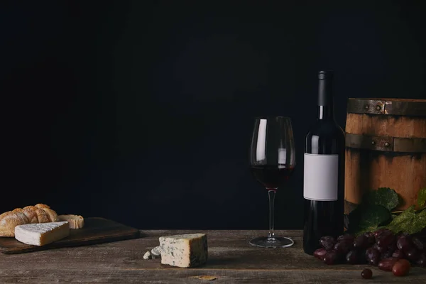 Vue rapprochée du verre, de la bouteille et du tonneau de vin sur une table en bois — Photo de stock