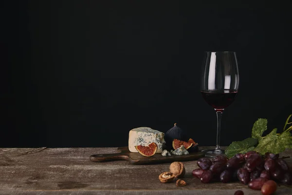 Келих червоного вина, сиру та свіжих фруктів на дерев'яному столі — стокове фото