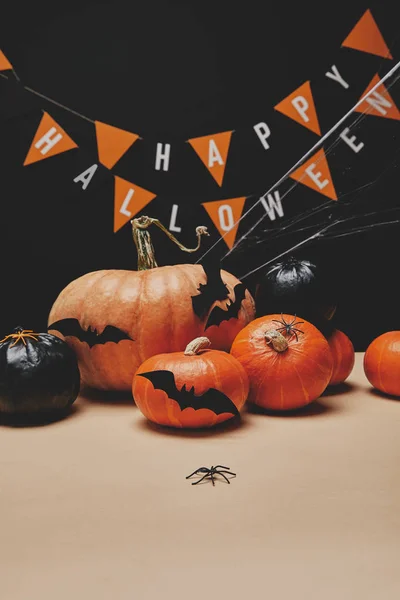 Kürbisse, Papierfledermäuse, Spinnen und Papiergirlanden mit fröhlichen Worten zu Halloween — Stockfoto