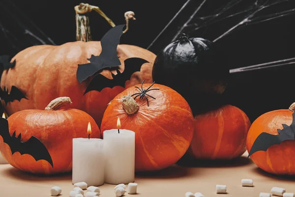 Candles with flame, pumpkins, paper bats and scattered marshmallows on table, halloween concept — Stock Photo