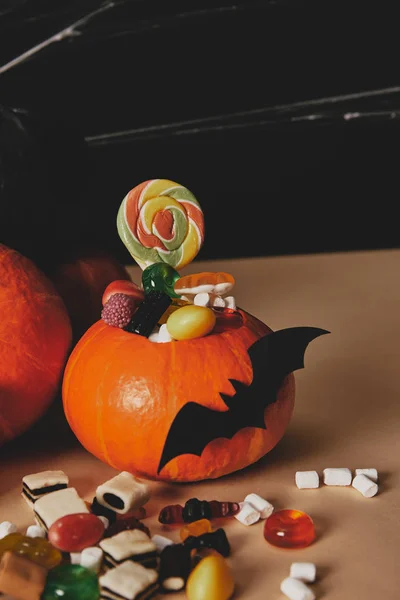 Calabazas, murciélago de papel y caramelos en la mesa, concepto de Halloween - foto de stock