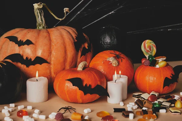 Pumpkins, jelly candies, marshmallows and paper bats on table, halloween concept — Stock Photo