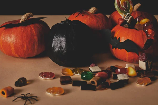 Calabazas, sabrosos caramelos de jalea y murciélagos de papel en la mesa, concepto de Halloween - foto de stock