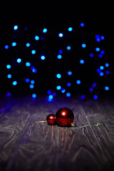Rote Weihnachtskugeln auf Holztisch mit blau glitzerndem Hintergrund — Stockfoto