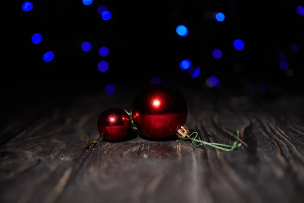 Shiny red christmas balls on wooden table with blue sparkling background — Stock Photo