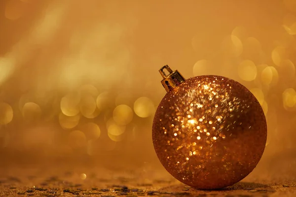 Goldene glitzernde Weihnachtskugel zur Dekoration auf Tischplatte mit Pailletten — Stockfoto