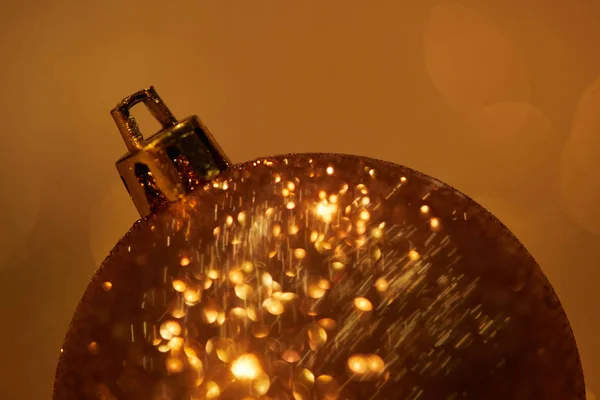 Close up of golden glittering christmas ball for decoration isolated on brown — Stock Photo