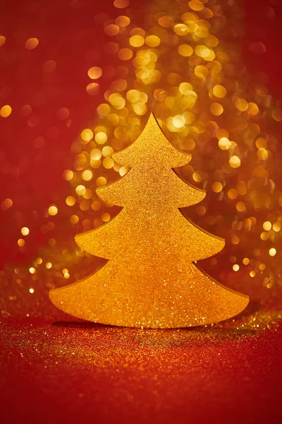 Árbol de navidad brillante dorado con brillo sobre fondo rojo - foto de stock