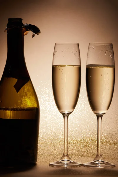 Gläser und Flasche Champagner mit Glitzer auf Tischplatte, Weihnachtskonzept — Stockfoto