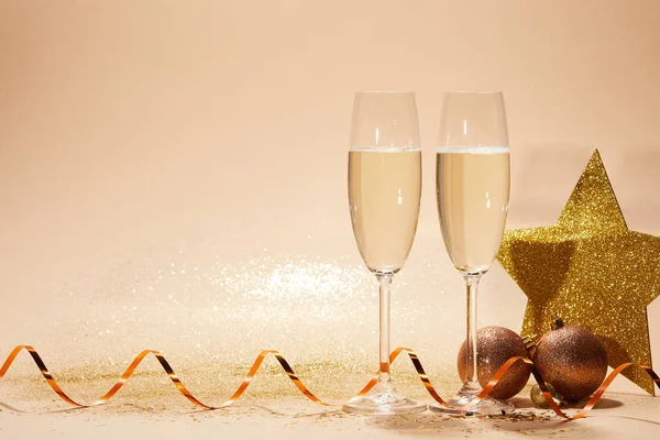 Jouets de Noël, étoile scintillante et deux verres de champagne avec des paillettes sur la table — Photo de stock