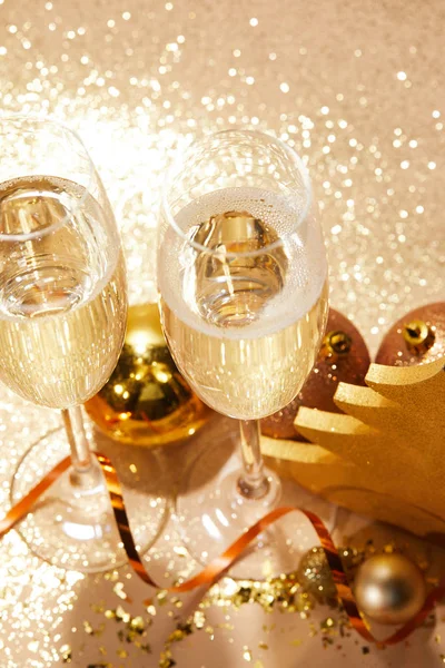 High angle view of christmas balls and two glasses of champagne with glitter on tabletop — Stock Photo