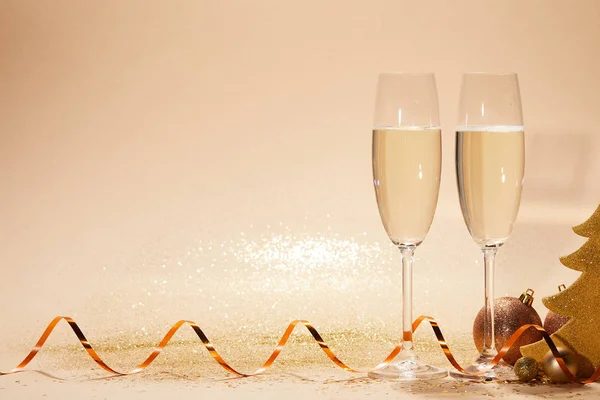 Рождественские игрушки, декоративная звезда и два бокала шампанского с блестками на столе — стоковое фото