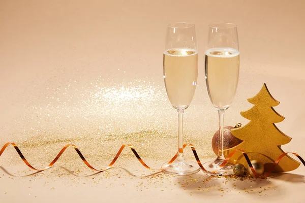 Two glasses of champagne with wavy ribbon and glitter on tabletop, christmas concept — Stock Photo