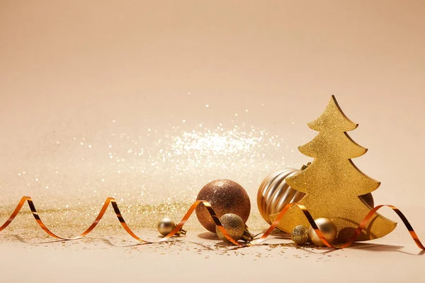 Christmas toys, decorative christmas tree, wavy ribbon and glittering sequins on tabletop — Stock Photo