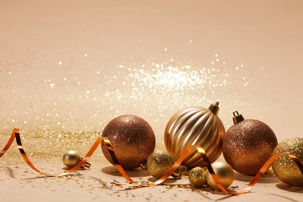 Brilhante bolas de Natal brilhantes e fita ondulada em mesa bege — Fotografia de Stock