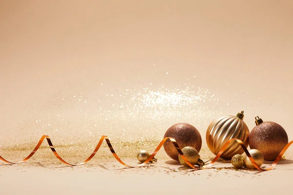 Brillantes bolas de Navidad brillantes y cinta ondulada en la mesa beige - foto de stock