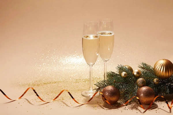 Brillantes bolas de Navidad, rama de pino y copas de champán en la mesa - foto de stock