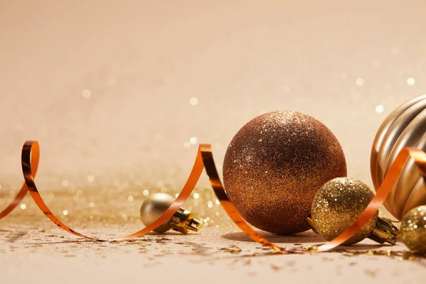 Close up of glittering bright christmas balls and wavy ribbon on beige tabletop — Stock Photo