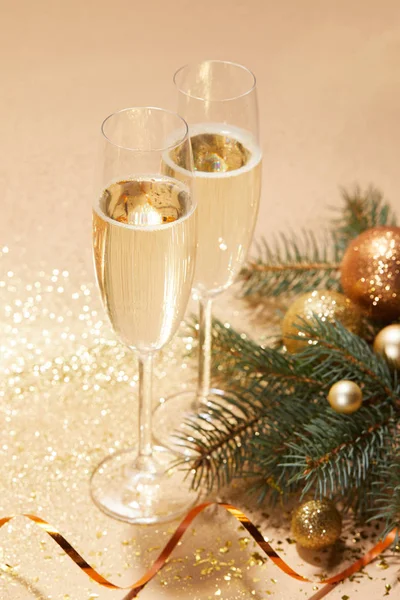 Bolas de Navidad de oro, rama de pino y copas de champán en la mesa - foto de stock