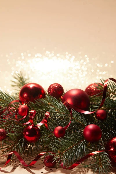 Red shiny christmas balls and pine branch on glittering tabletop — Stock Photo