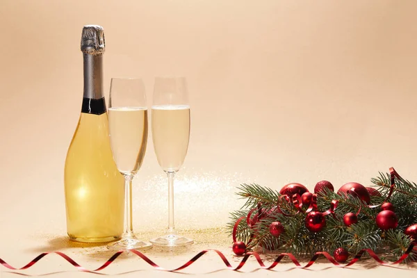 Пляшка та келихи шампанського, різдвяні кульки та соснова гілка на блискучому стільниці — стокове фото