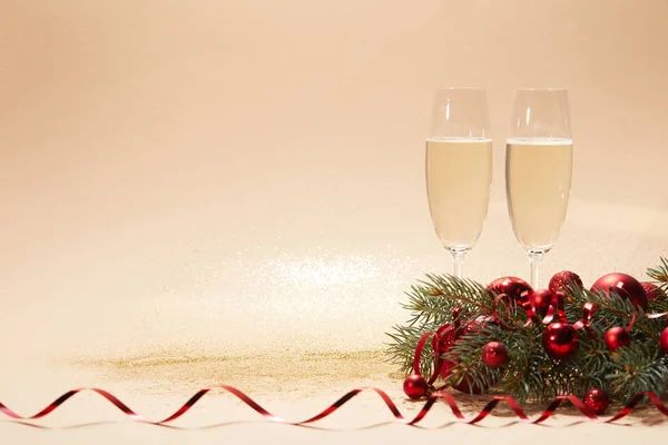 Copas de champán, bolas de Navidad brillantes y rama de pino en la mesa brillante - foto de stock
