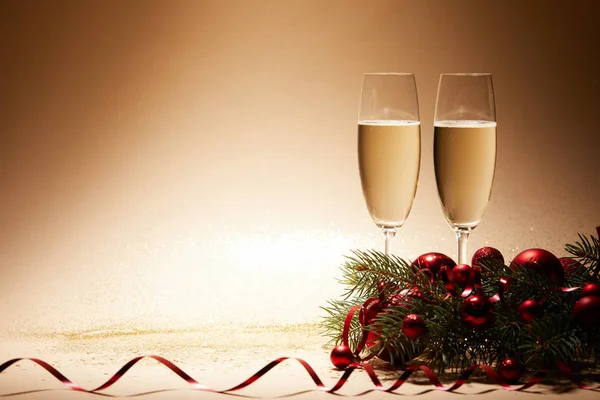 Copas de champán, bolas de Navidad y rama de pino en la mesa reluciente - foto de stock