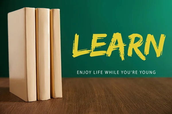 Three books on wooden table with chalkboard on background with 