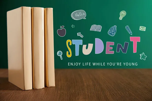 Three books on wooden table with chalkboard on background with 