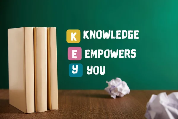 Three books on wooden table with chalkboard on background with 