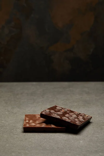 Deliciosas barras de chocolate com nozes no fundo cinza — Fotografia de Stock