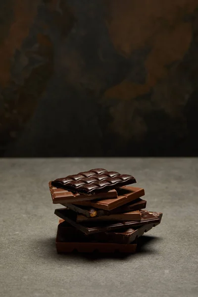 Vista ad angolo alto di pezzi di cioccolato impilati assortiti su grigio — Foto stock